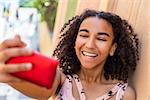 Beautiful happy mixed race African American girl teenager female child smiling with perfect teeth taking selfie photograph with cell phone