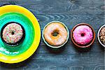 Colorful Donuts breakfast composition with different color styles of doughnuts over an aged wooden desk background.