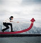 Determinated businessman with much effort lifts statistics arrow with a rope in a skyscraper roof