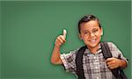 Cute Hispanic Boy with Thumbs Up Wearing Backpack In Front of Blank Chalk Board.