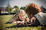 Portrait of a teenage girl lying down on a grassy field with her boyfriend.