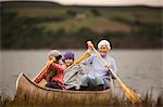 Senior woman paddling in a canoe with her two granddaughters.