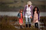 Mature woman walking hand in hand with her two granddaughters.