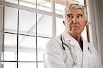 Portrait of worried looking doctor sitting in corridor.