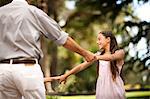 Father and daughter dancing in a park.