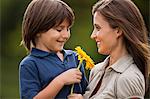 Young boy giving his mother a sunflower.