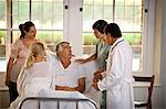 Elderly man receiving a hospital visit from his family.