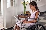 Young girl sitting in wheelchair typing on laptop.