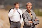 Tough and sensible young businesswoman with her male colleague in the background.