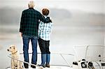 Man and his grandson standing on the deck of a boat and looking at the view.