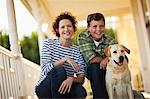 Portrait of mature woman crouching on the porch with her son and their dog.