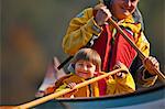 Happy grandfather and young grandson canoeing together on a lake.