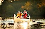 Happy grandfather and young grandson canoeing together on a lake.