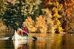 Grandfather canoeing on river with grandson.