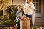 Boy helping his grandfather gather leaves in the backyard.