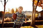 Portrait of running boy holding his rugby ball in the backyard.