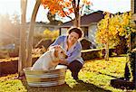 Mid-adult woman giving her dog a bath in the backyard.