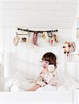 Sweden, Small girl (2-3) sitting in bed and embracing doll