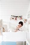 Sweden, Small girl (2-3) sitting in bed and embracing doll