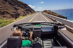 USA, Hawaii, Oahu, Banzai Pipeline, Rear view of mid adult woman driving convertible car