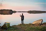 Finland, Pirkanmaa, Tampere, Pyhajarvi, Mid adult man taking pictures on lake shore