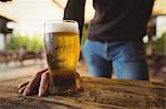 Mid section of man with glass of beer at bar