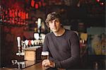 Portrait of man with a glass of beer at bar counter in bar