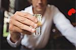 Close-up of bartender holding tequila shot glass at bar counter in bar