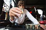 Portrait of bartender holding tequila shot glass at bar counter in bar