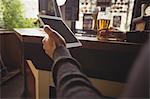 Man using digital tablet with glass of beer in hand at bar