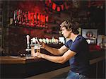 Man with glass of beer using mobile phone in counter at bar