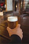 Man holding glass of beer at bar