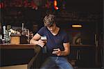 Man using mobile phone while having glass of beer in bar