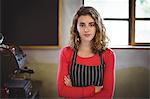 Confident waitress standing with arm crossed in Café at bicycle shop