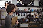 Mechanic standing with clipboard in bicycle shop