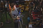 Mechanic carrying a bicycle in bicycle workshop