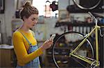 Mechanic using mobile phone in bicycle shop