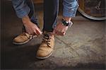 Mechanic tying shoe lace in bicycle workshop