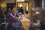 Mechanic using mobile phone at counter in workshop