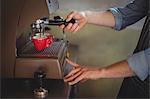 Mid section of waiter making coffee in Café at workshop