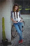 Beautiful woman leaning on wall with vintage camera