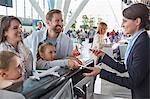 Customer service representative helping family checking in with tickets at airport check-in counter