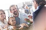 Customer service representative helping family with tickets at airport check-in counter