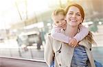 Portrait smiling mother piggybacking daughter outside airport
