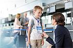 Flight attendant talking to child traveler in airport