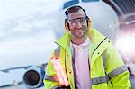 Portrait smiling air traffic controller in front of airplane on tarmac