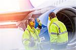 Airport ground crew workers talking near airplane