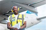 Air traffic controller with clipboard under airplane on airport tarmac