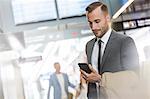 Businessman texting with cell phone in airport concourse