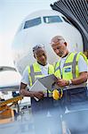 Air traffic controllers with clipboard below airplane on airport tarmac